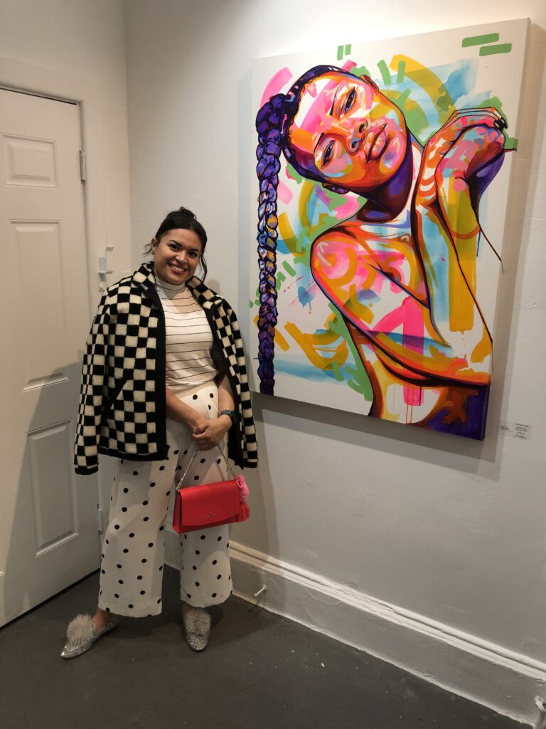 Sicerra, curator of Oakland's Metalhaus Gallery in Pendelton, Michael Kors, Banana Republic, & Kate Spade stand in front of painting on white wall