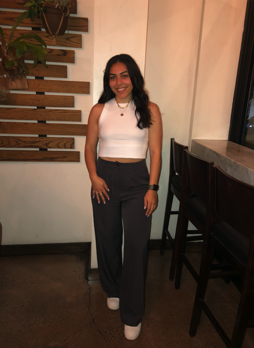 woman stands with slacks and white top in a restaurant