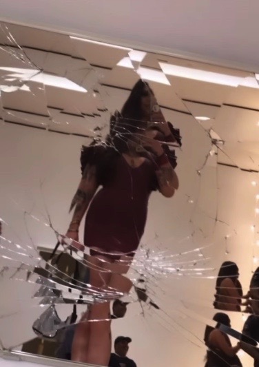 The author of the article takes a selfie in a cracked mirror in a plum latex dress at the SF MoMA art bash