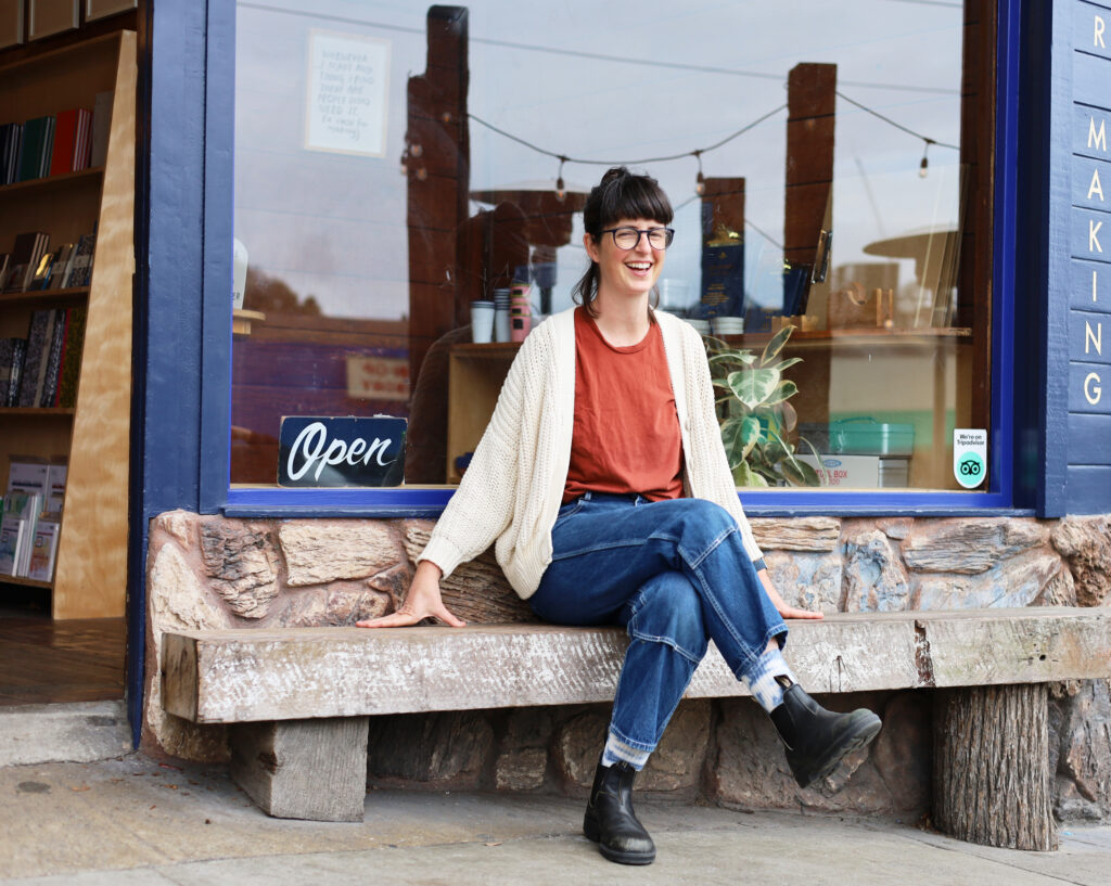 Alexis Joseph sitting on a wooden bench in front of Case For Making Art Supplies