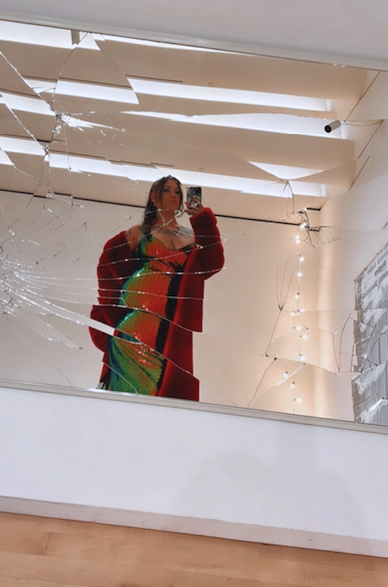 Description: The author of the story poses in a rainbow sequined gown and long red fur coat poses in front of a cracked mirror