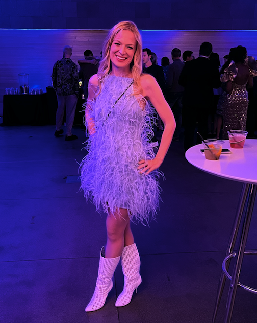 Description: A woman poses in a light blue mini dress made of ostrich feathers and white boots.