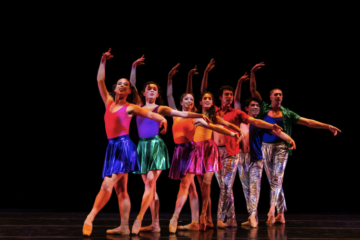 The OBC cast in rainbow costumes for "Rainbow Dances"