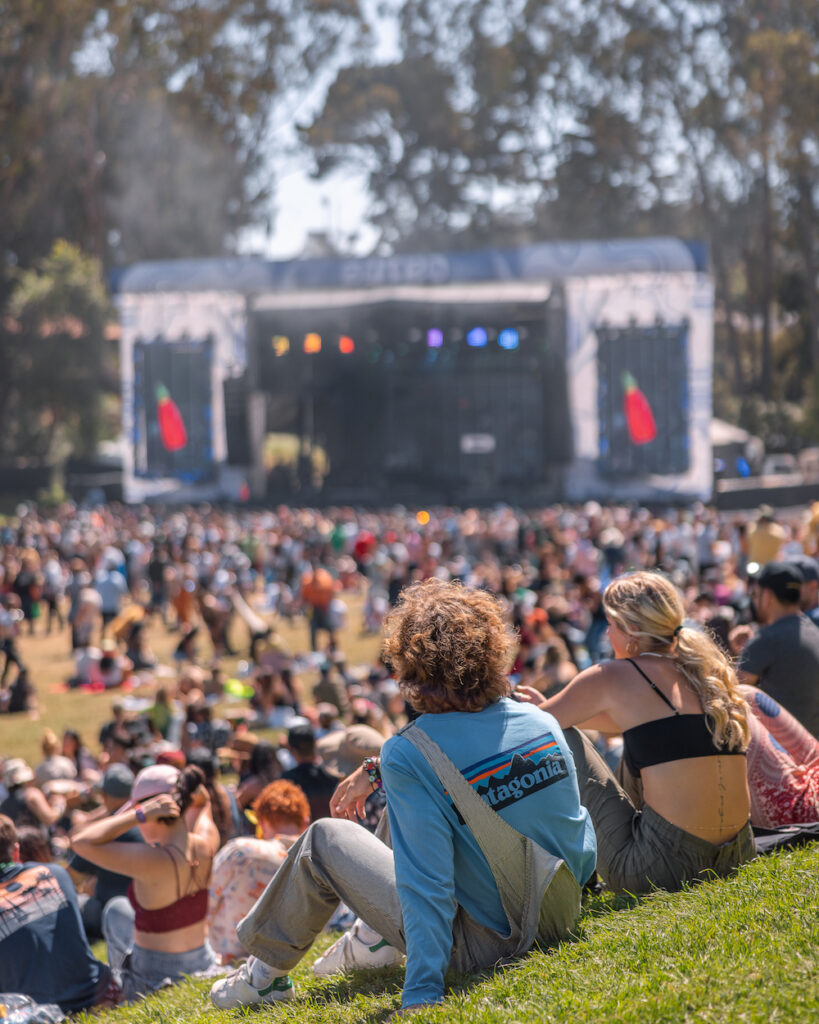 a couple sits on a grassy hill facing the Sutro Stage