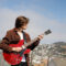 Musician Asher Belsky holds a Gibson guitar with the city of San Francisco behind him